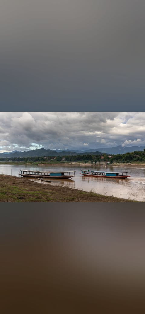 Boats on the Mekong with dark clouds and blue sky… wallpaper in sage green and sand tones, Full HD, 16:9 format for phone